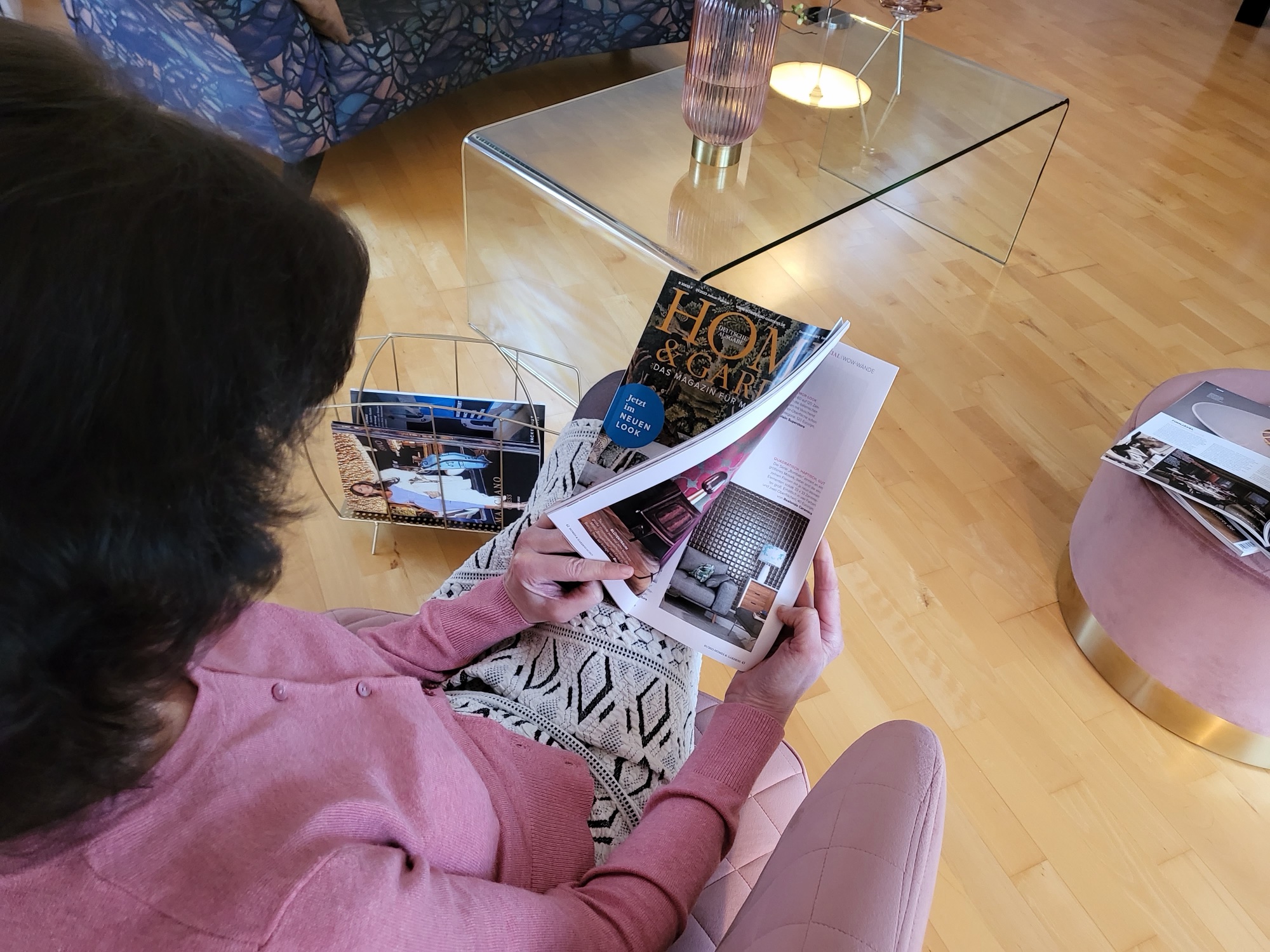 Person liest das Magazin Homes & Gardens in einem elegant eingerichteten Raum